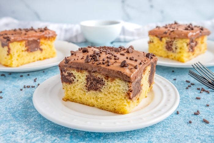 three slices of yellow cake with chocolate frosting on a white plate