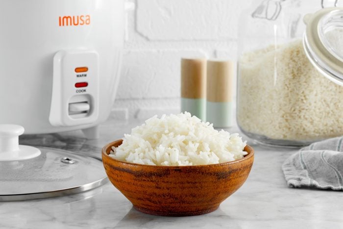 wooden bowl filled with white rice on a kitchen counter