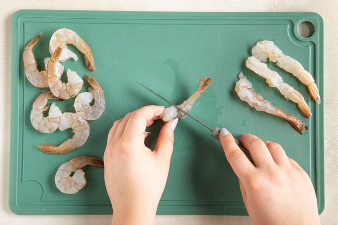 hands preparing raw shrimp shrimp a cutting board