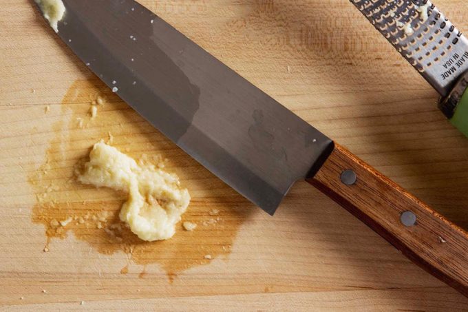 wood cutting board with knife and crushed garlic