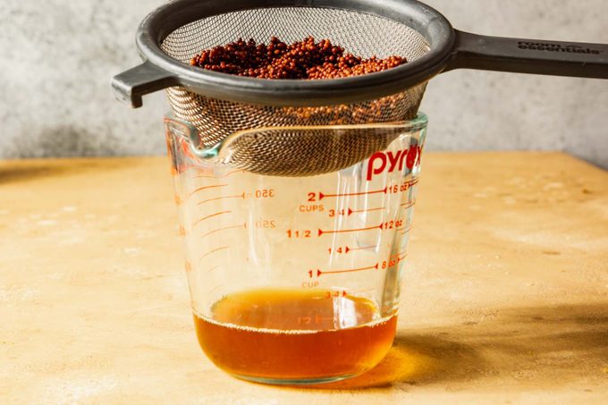 mustard seeds draining in strainer with a glass measuring cup underneath to catch the liquid