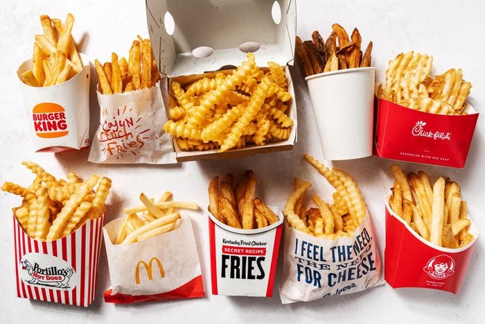 a grid of a variety of fries from different fast food restaurants in their branded to go containers, on a white background