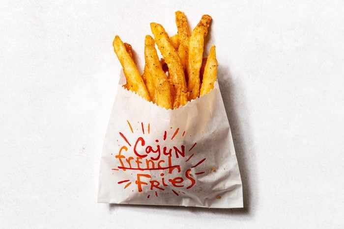 Popeyes fries in a wax bag with cajun French fries written on the front of the bag