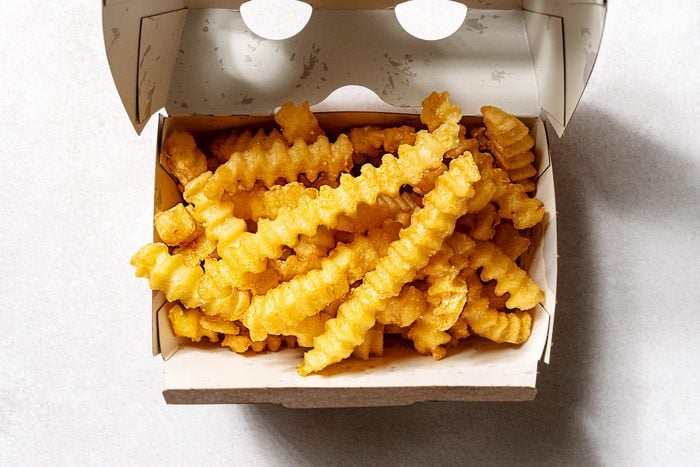 view from above of Shakeshack crinkle fries in a cardboard to go box, on a white background
