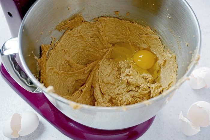 egg added to cookie batter in a kitchenmaid mixing bowl