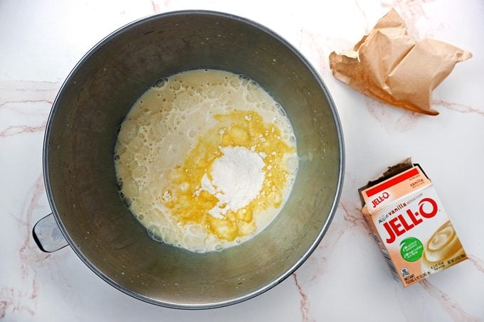 Making vanilla Jello pudding in a large stainless steal bowl on a white marble kitchen counter