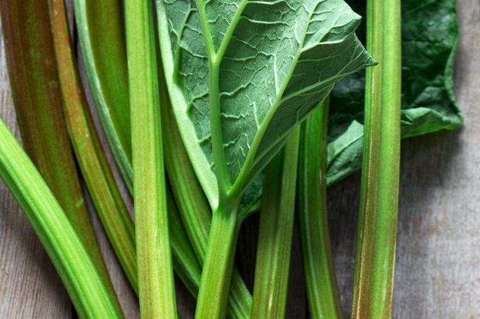Stems and leaves of rhubarb on a wooden background.