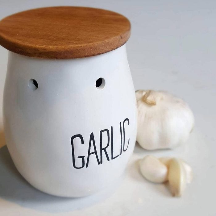 Garlic Keeper on a kitchen counter next to a head and cloves of garlic