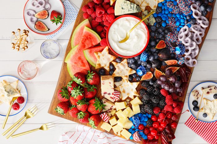 fourth of july themed charcuterie board with red white and blue fruits and cheese