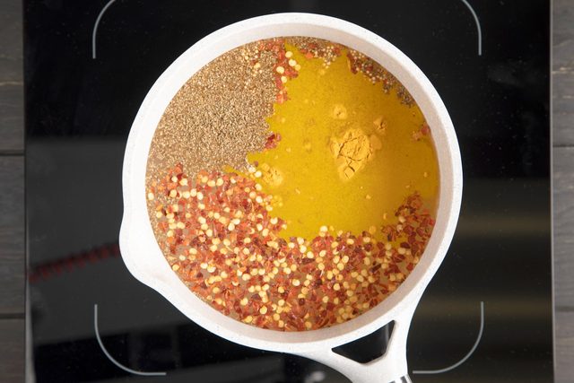 spices floating in a brine for pickled cauliflower in a pan on a stovetop