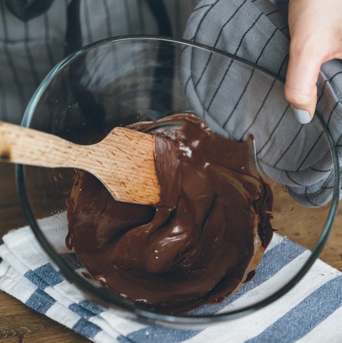 Chocolate pudding in wooden spoon on the cooker