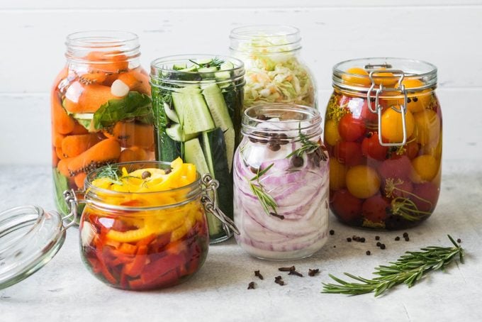 Pickled vegetables in various sized glass jars on a kitchen counter
