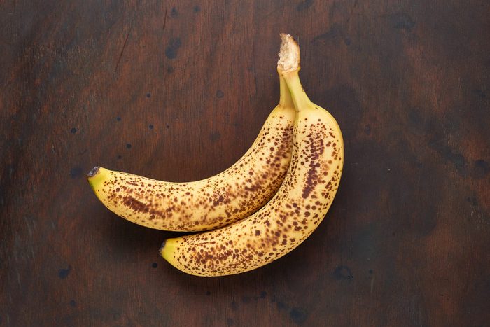 Bunch of organic spotted bananas top view flat lay on stone background modern. Copy space.