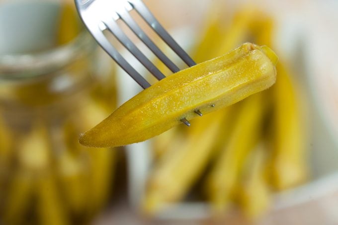Pod of pickled okra skewered on fork