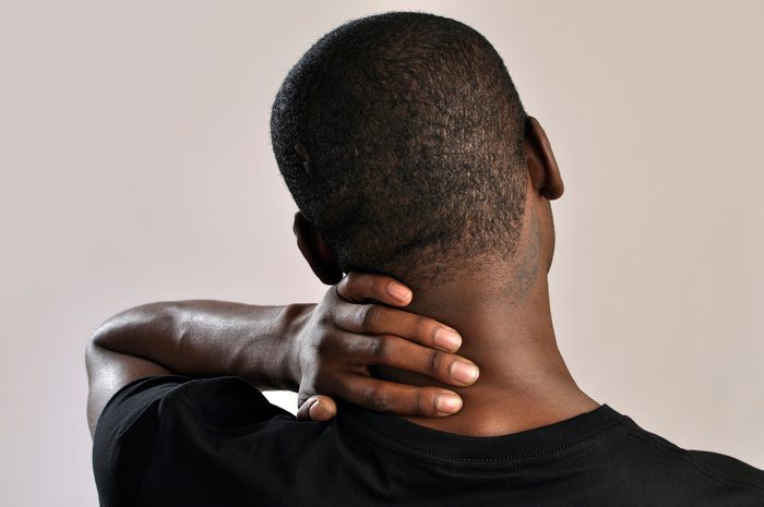 Hombre sosteniendo la parte posterior de su cuello causa de dolor