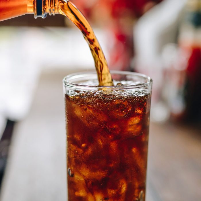 Pouring cola water into the glass.