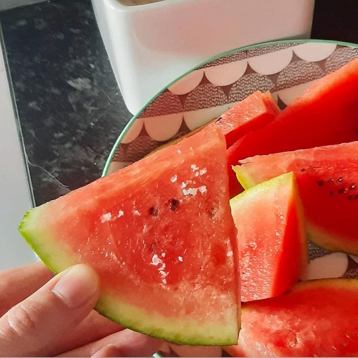 hand holding a slice of watermelon with salt