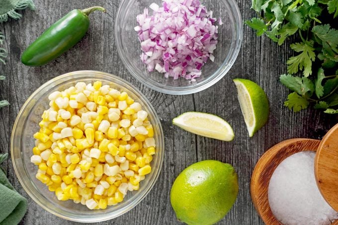 bowl of corn and onions and other ingredients on the counter for corn salsa
