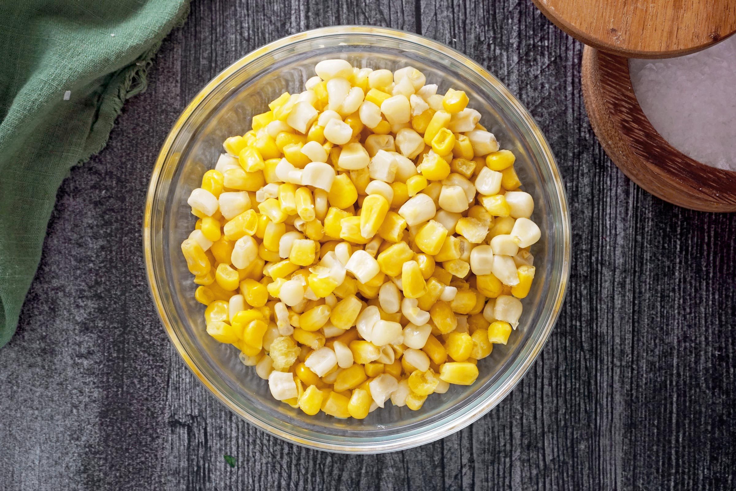 corn kernnels in a clear glass bowl on a wooden countertop