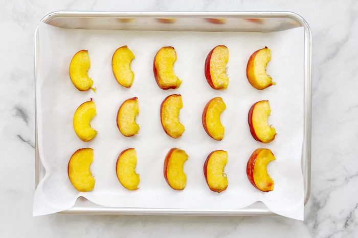peach slices on a cookie sheet with parchment paper