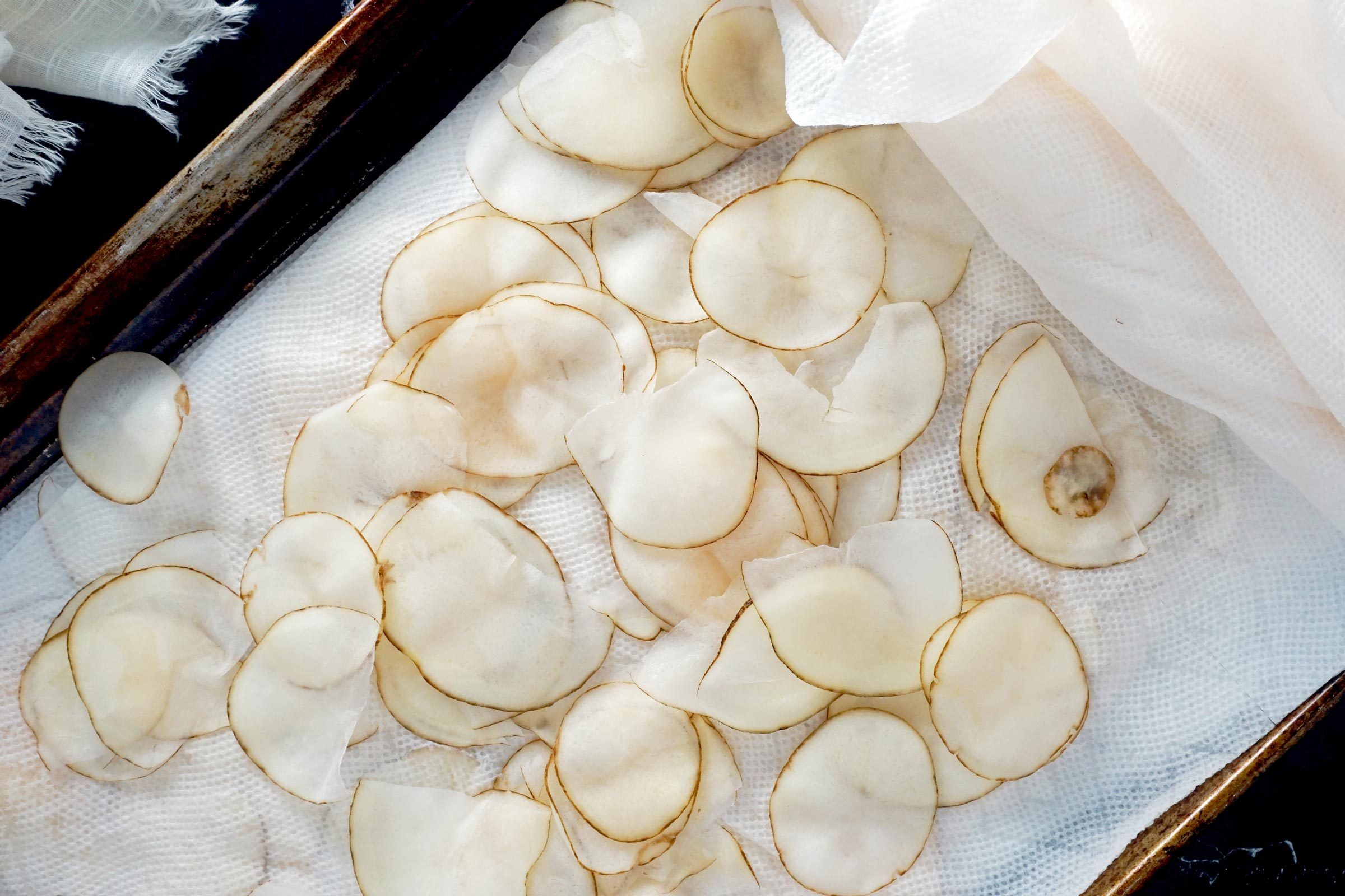 potato chips drying on a baking sheet