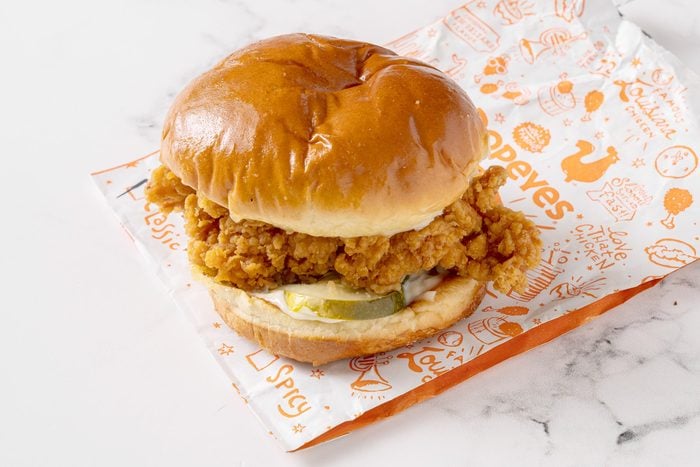 Popeye's chicken sandwich with its packaging on a white kitchen counter