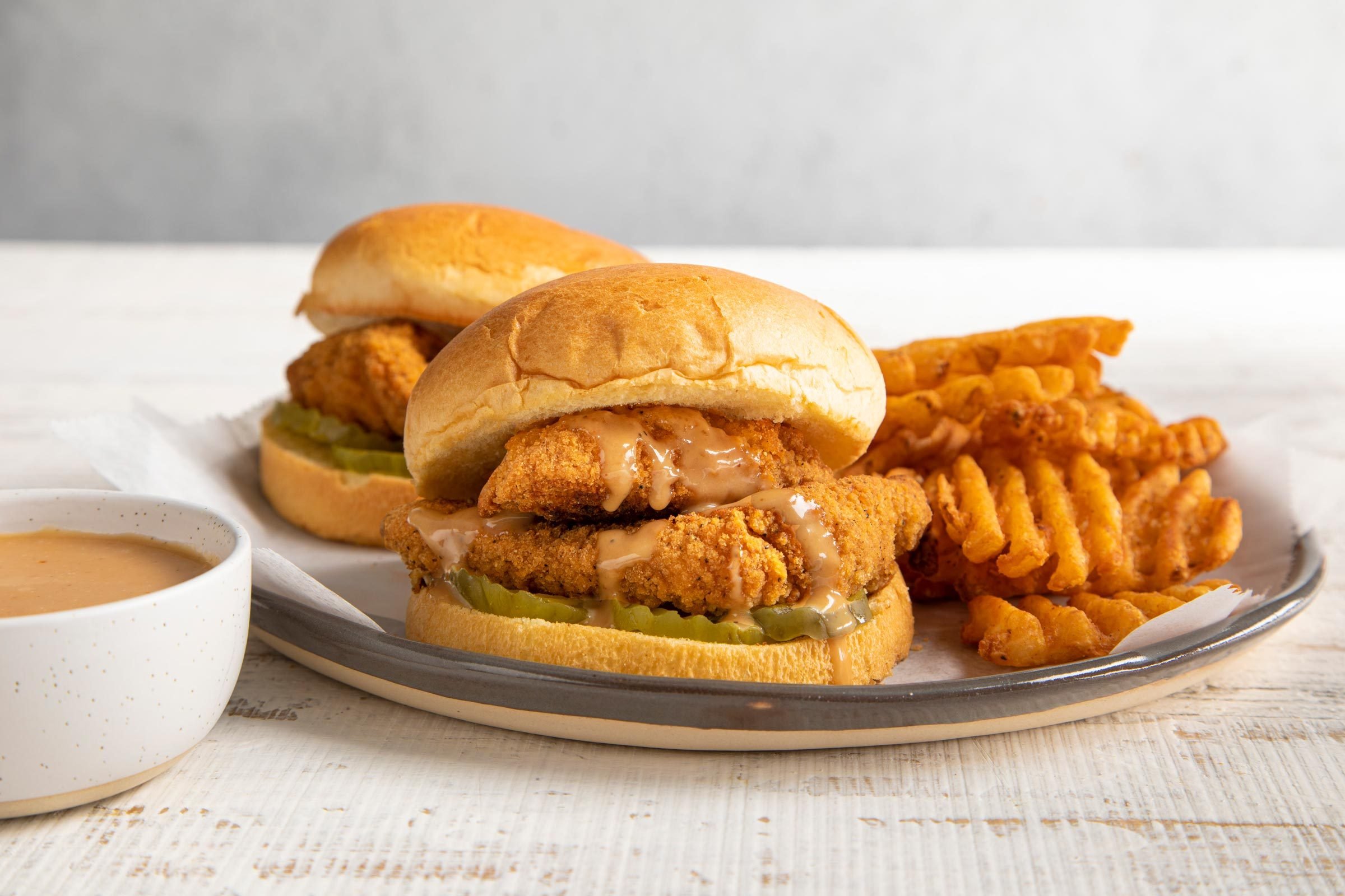 fried chicken sandwiches on a plate with a side of chick fil a sauce