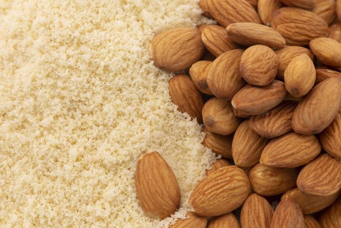 full frame of almond flour next to a pile of whole almonds