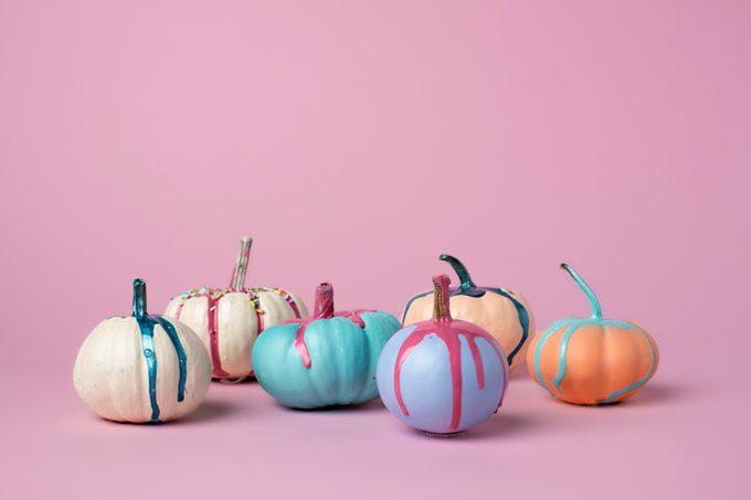 colorful pumpkins with dripping paint on pink background