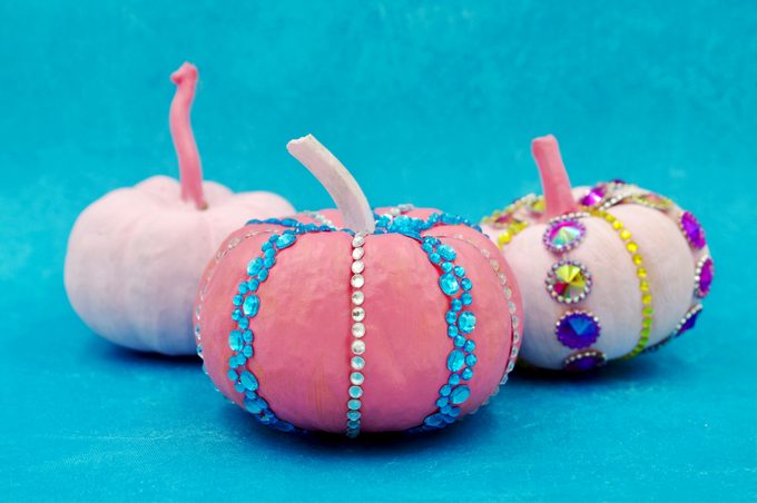 three painted Pumpkins with jewels on a blue background