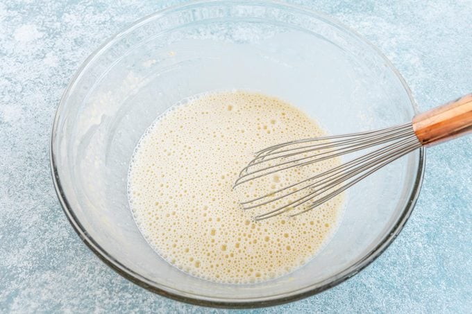 mixing flour, sugar, milk and egg in a glass bowl with a whisk