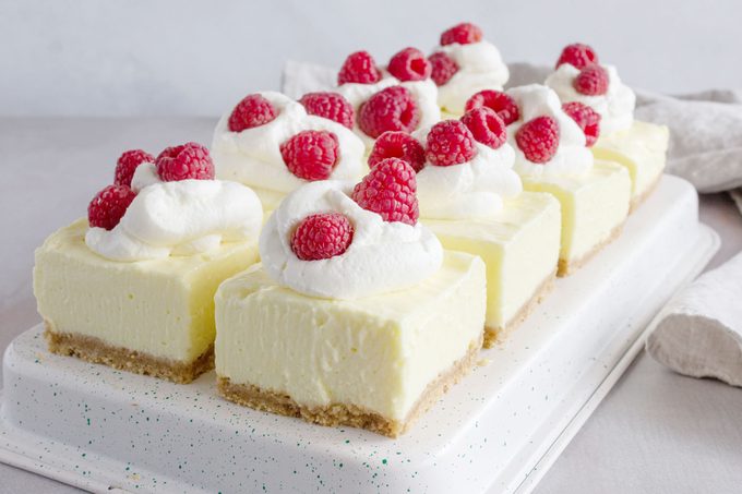No Bake Pudding Cheesecake bars topped with cream and raspberries