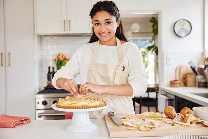 Sahana Vij arranging pears on the top of a tart in her kitchen