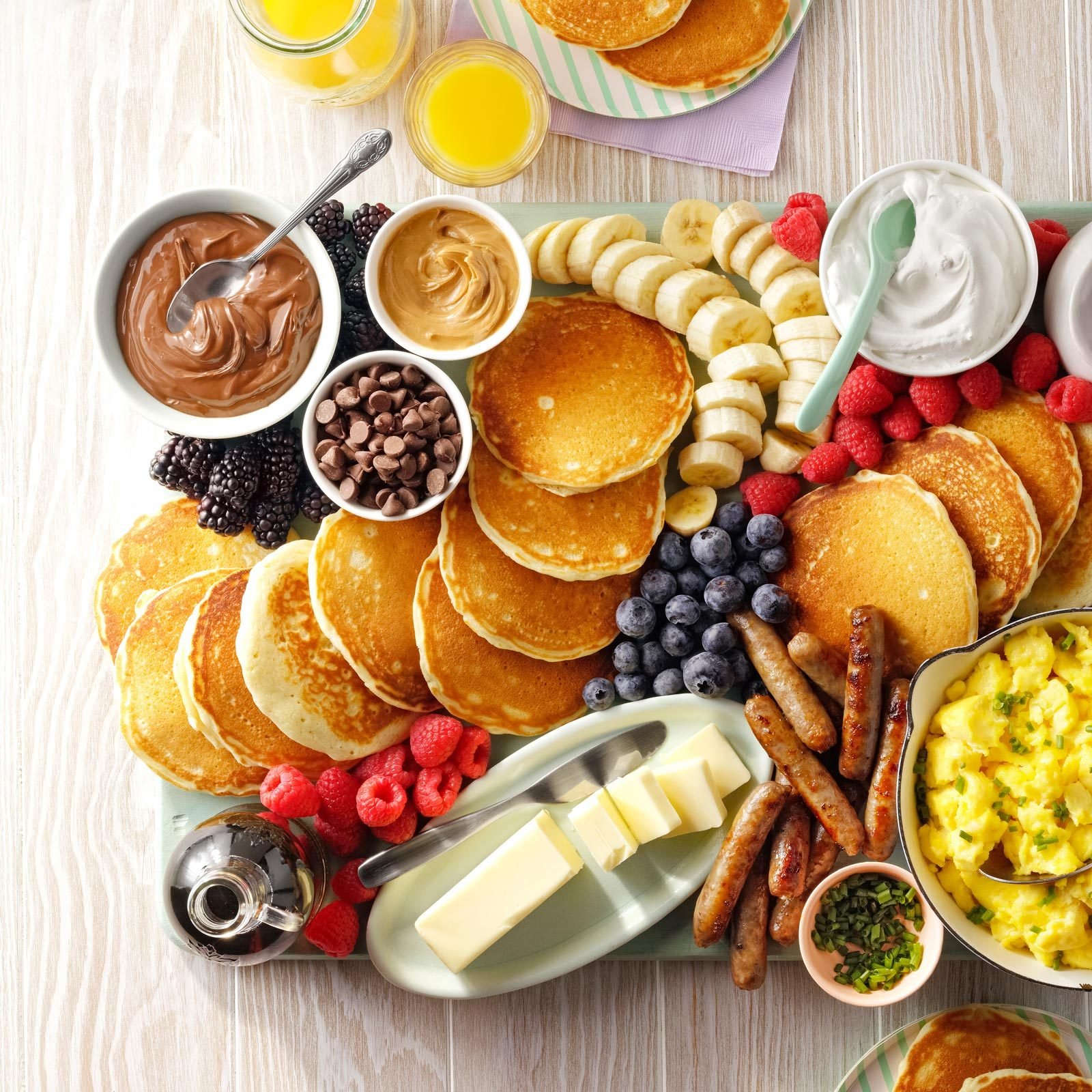 breakfast charcuterie board with pancakes, fruit, and eggs