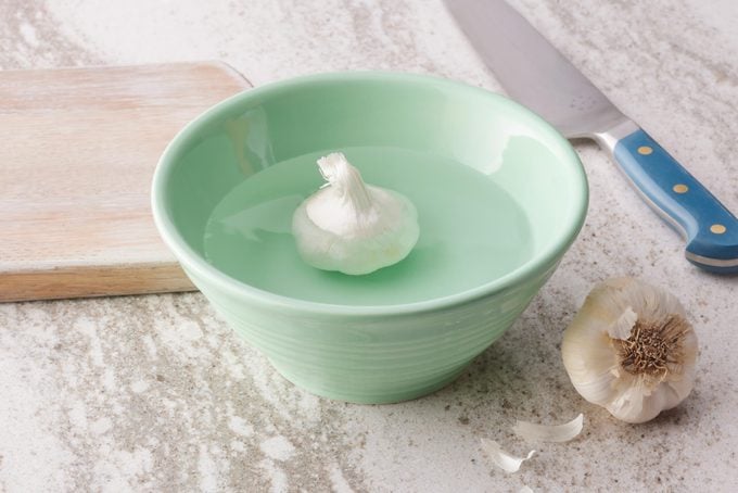 unpeeled garlic in a small bowl of water