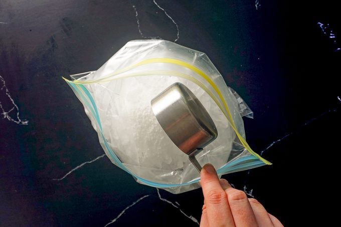 adding salt to the ice in the gallon size ziploc bag on dark marble background