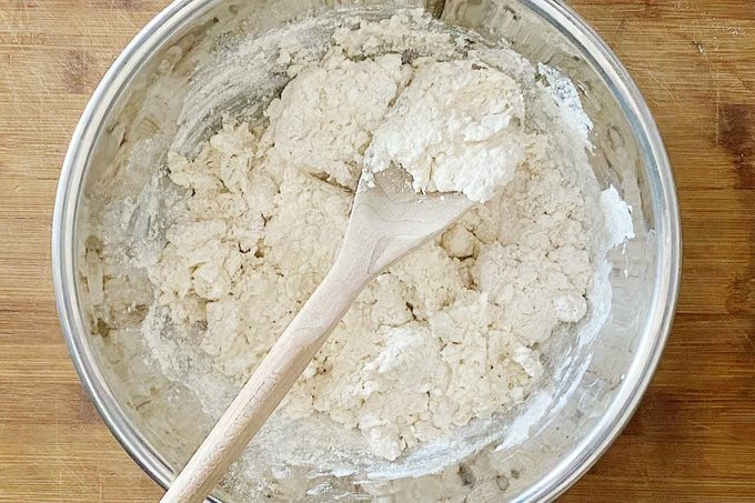 mixing dough with a wooden spoon i na large glass bowl