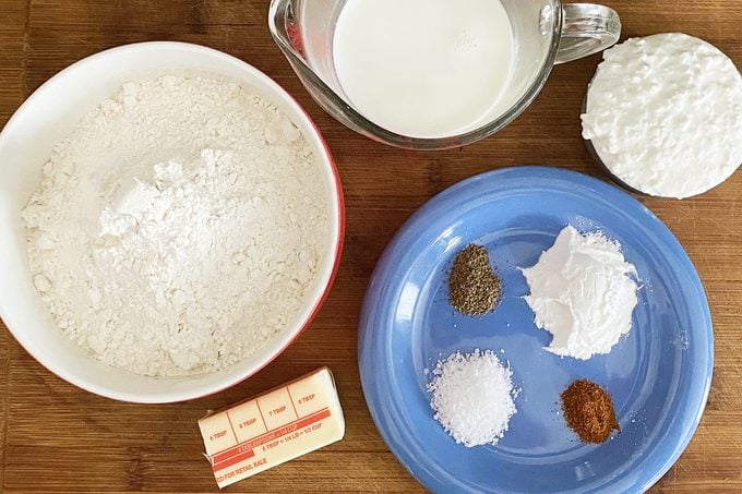 ingredients for Cottage Cheese Biscuits measured out into various bowls on a wooden table
