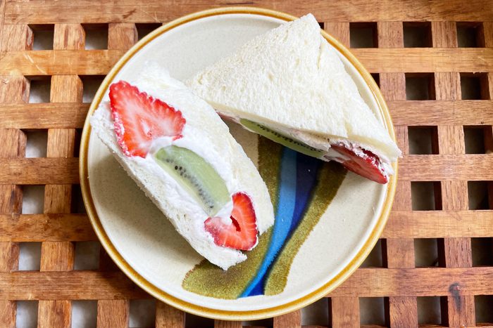 Japanese Fruit Sandwich with kiwi and strawberries sliced in triangles on a plate, with a wooden background