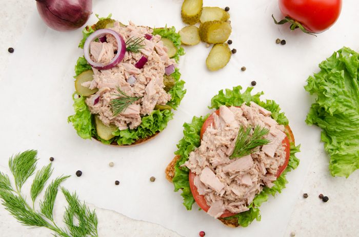 Flat lay view at Tuna sandwiches with lettuce tomatoes pickles and onions on parchment paper