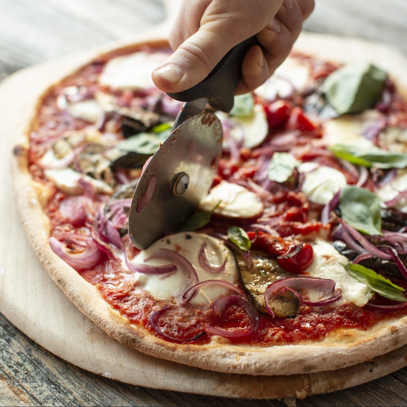 Close-Up Of Pizza On Table Being Cut