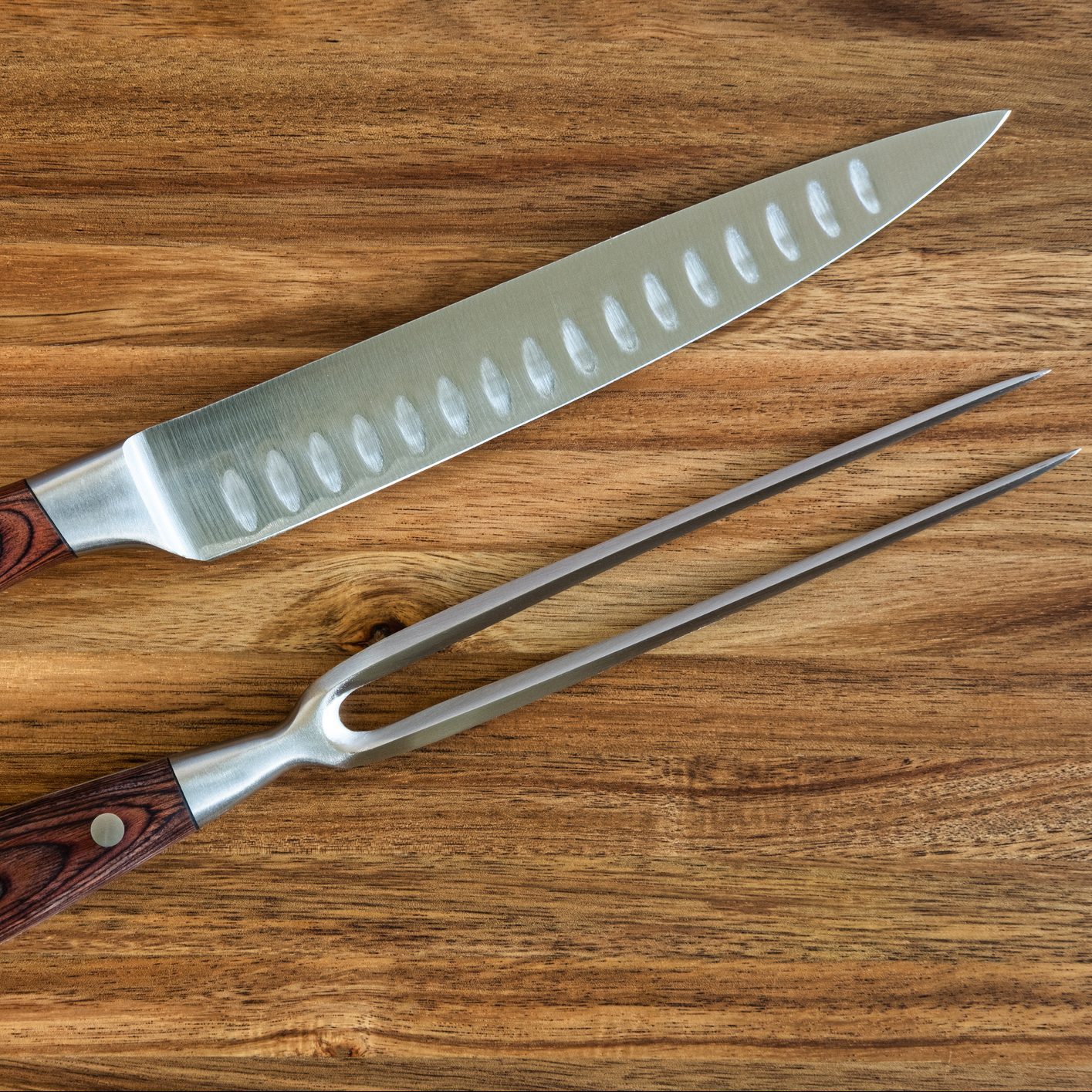 a knife and fork meat carving set on a wooden cutting board