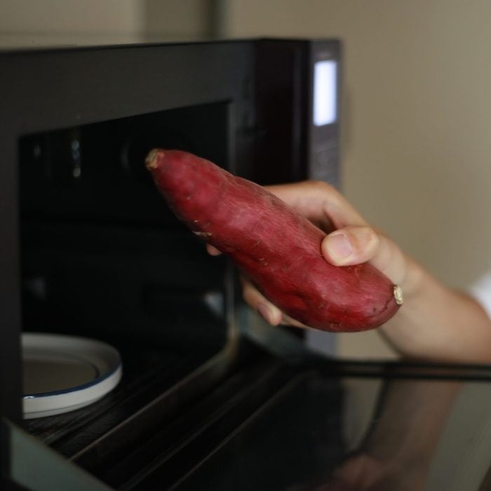 A man trying to heat sweet potatoes in the microwave