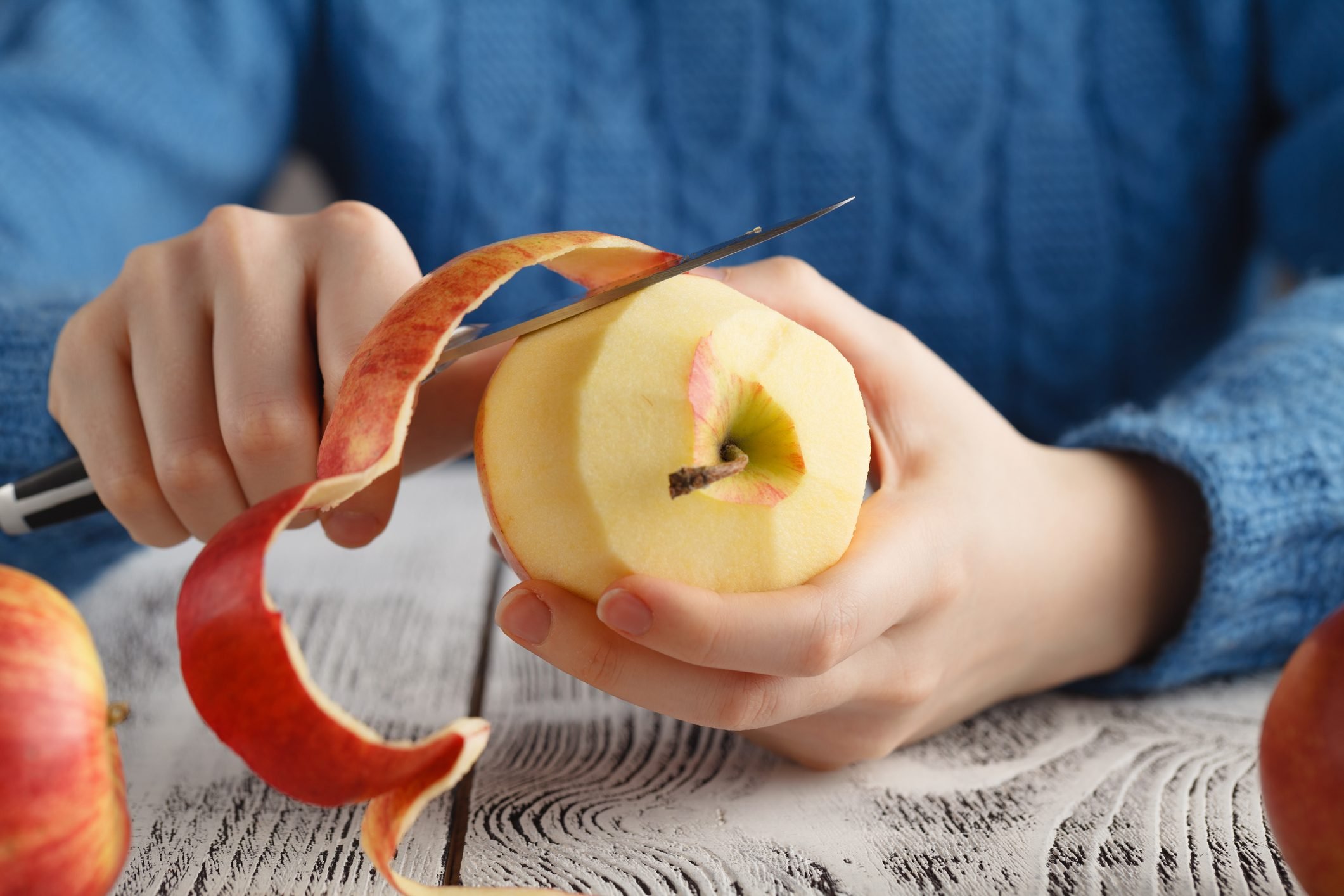 Girl peeling an apple on table