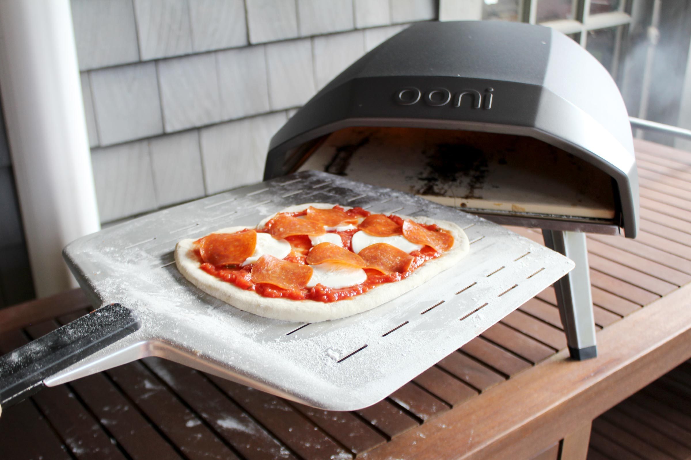 putting a pepperoni pizza into the Oonie pizza oven