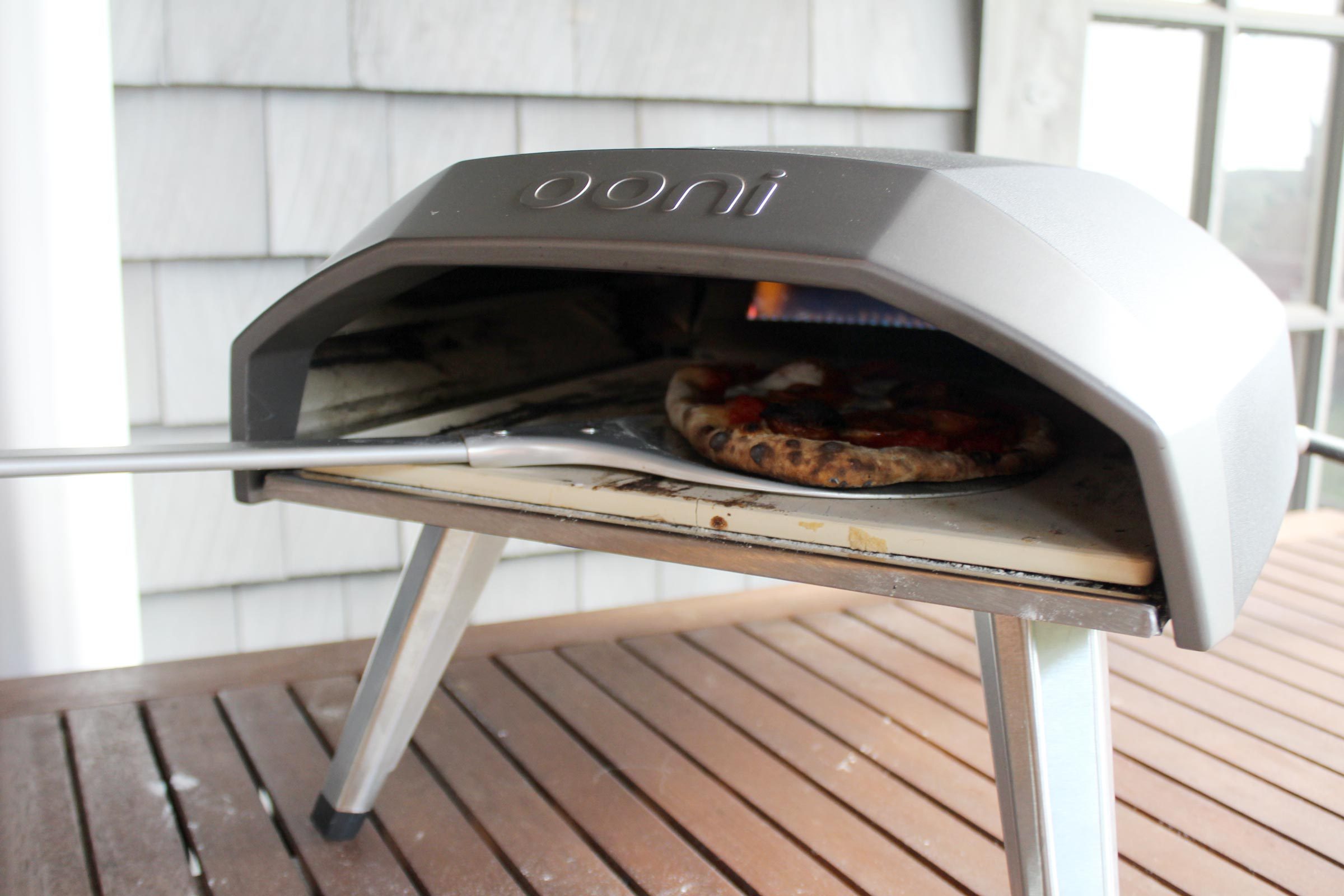 a pizza on a pizza peel inside the oonie oven