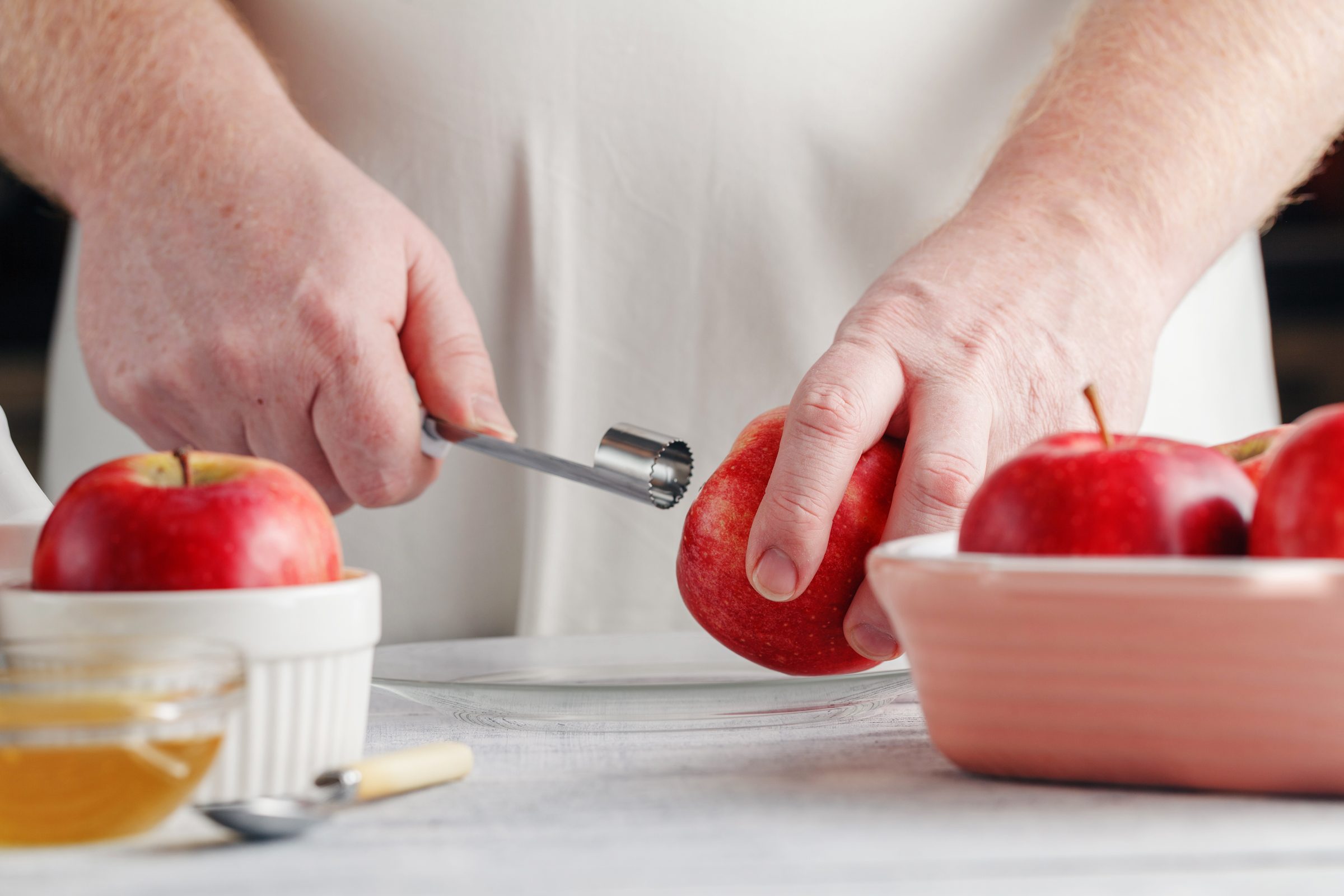 close up of hands holding a red apple and an apple corer In the other hand