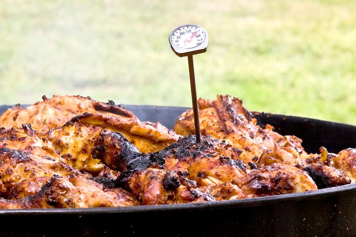 chicken on a grill outside with a meat thermometer sticking out