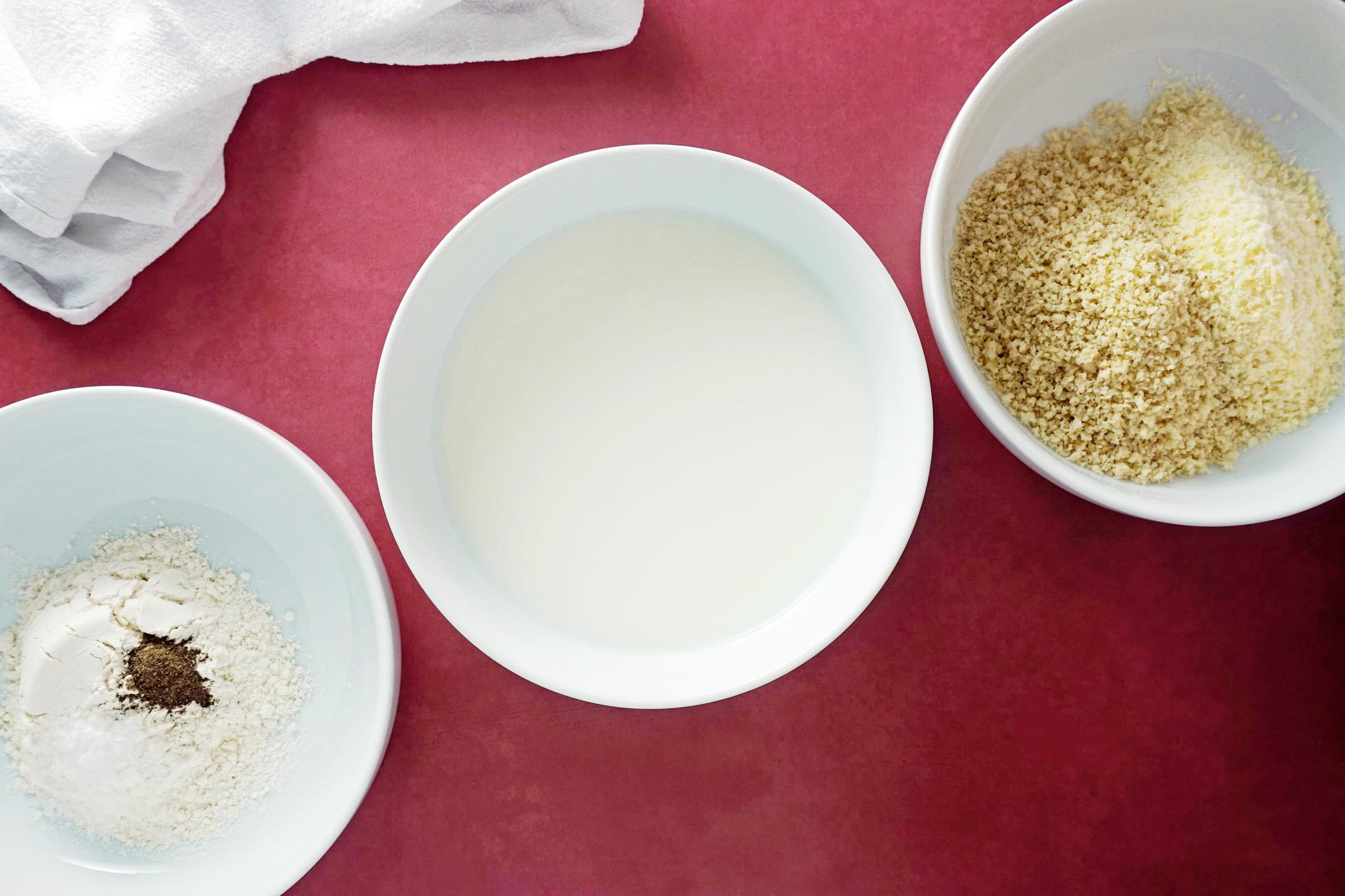 three small bowls with flour, milk, and bread crumbs