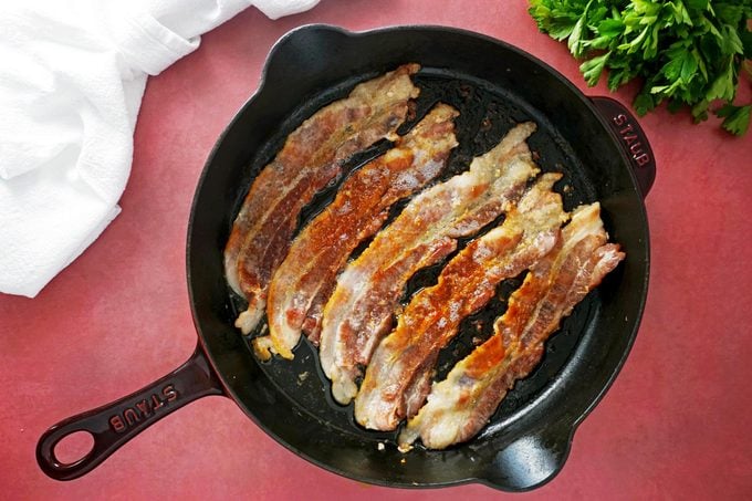 cooking bacon in a cast iron pan, view from above